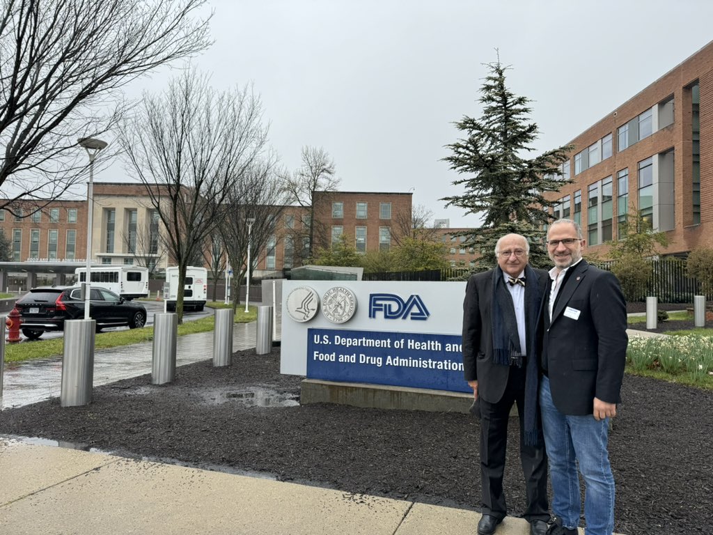 Two gentlemen stand in front of a sign for the FDA that says U.S. Department of Health and Food and Drug Administration