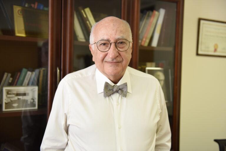 A gentleman in a white collared shirt and bow tie looks into the camera.