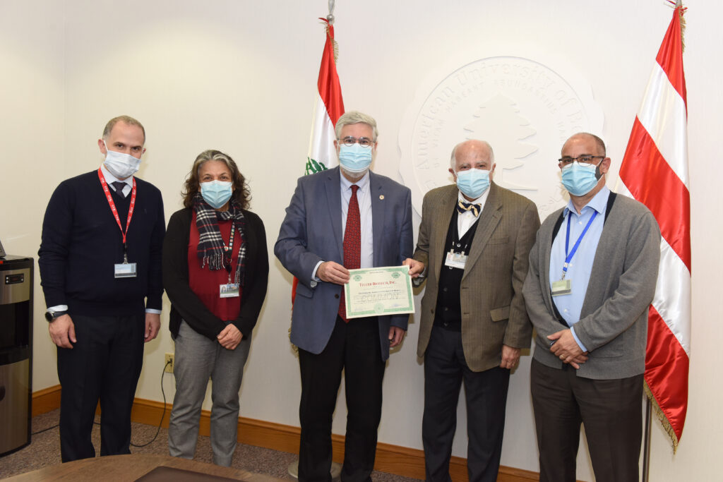 A group of 5 individuals in professional attire, wearing medical masks, and holding a certificate.